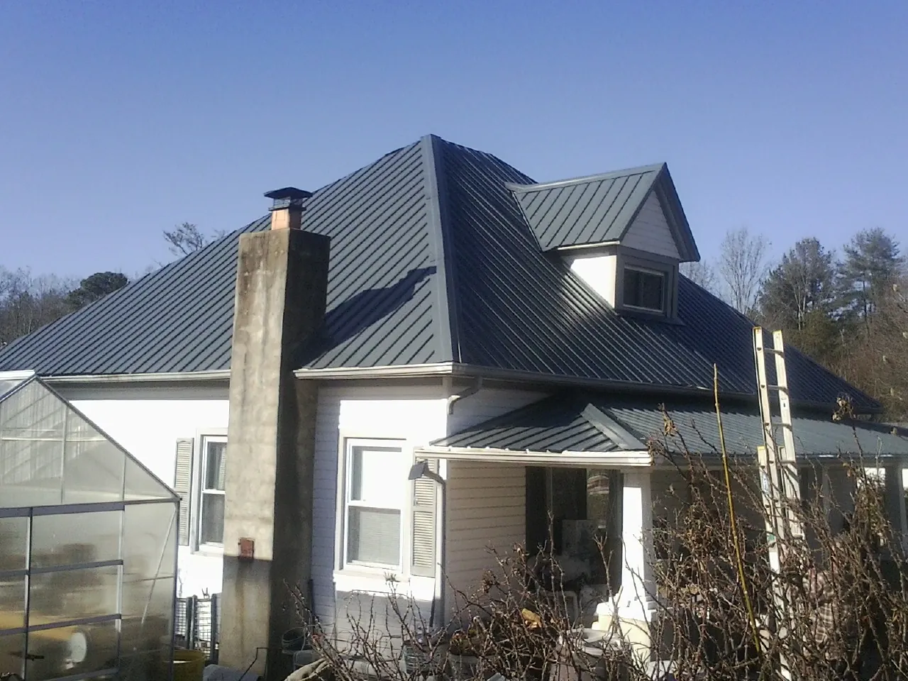 Dark blue standing seam metal roof on a white farmhouse with dormer — Slate & Tile Roof Repair by Roofing Brothers in Provo