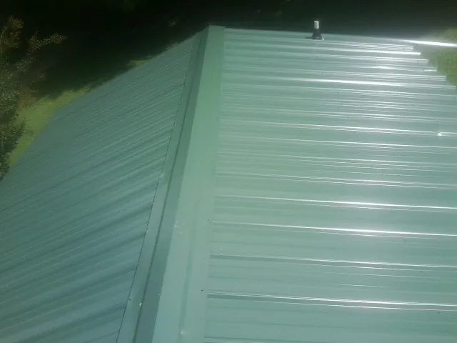New green metal panels meeting at the ridge of a roof — Flat Roof Repair work by our crew in Provo