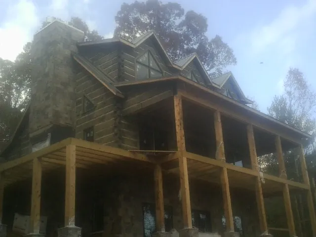 Stone chimney and dormers on a large log home with a timber porch in Provo