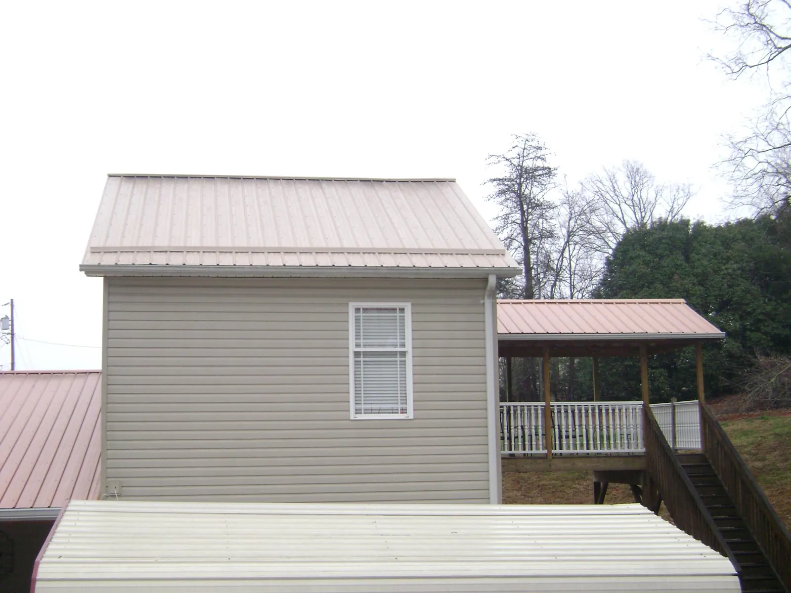Tan metal roofs on a two story addition and attached porch, from a Roof Replacement job in Provo