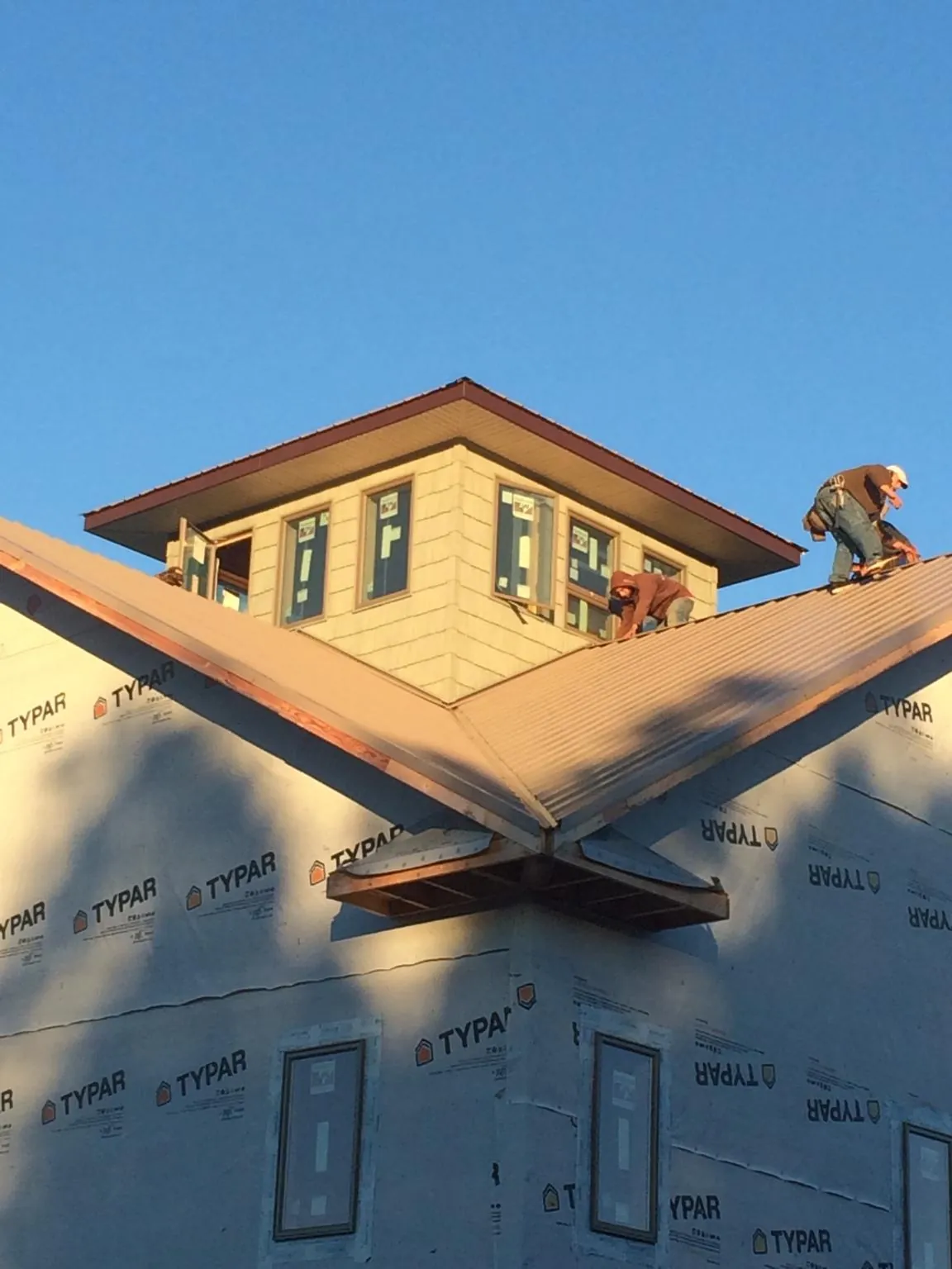 Roofers working around a rooftop cupola on a new metal roof at sunset — Roof Waterproofing in Provo by Roofing Brothers